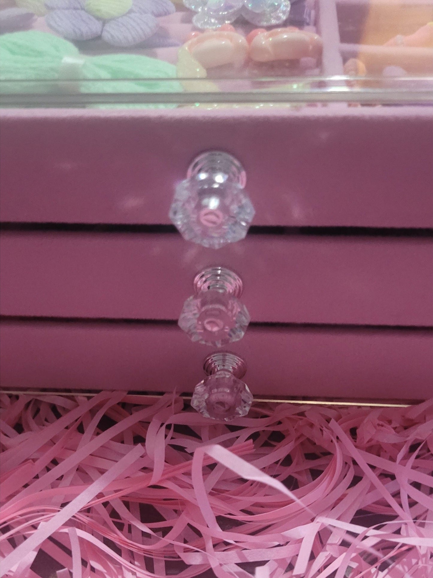 Close-up of a pink drawer with decorative glass knobs and pink ribbons.