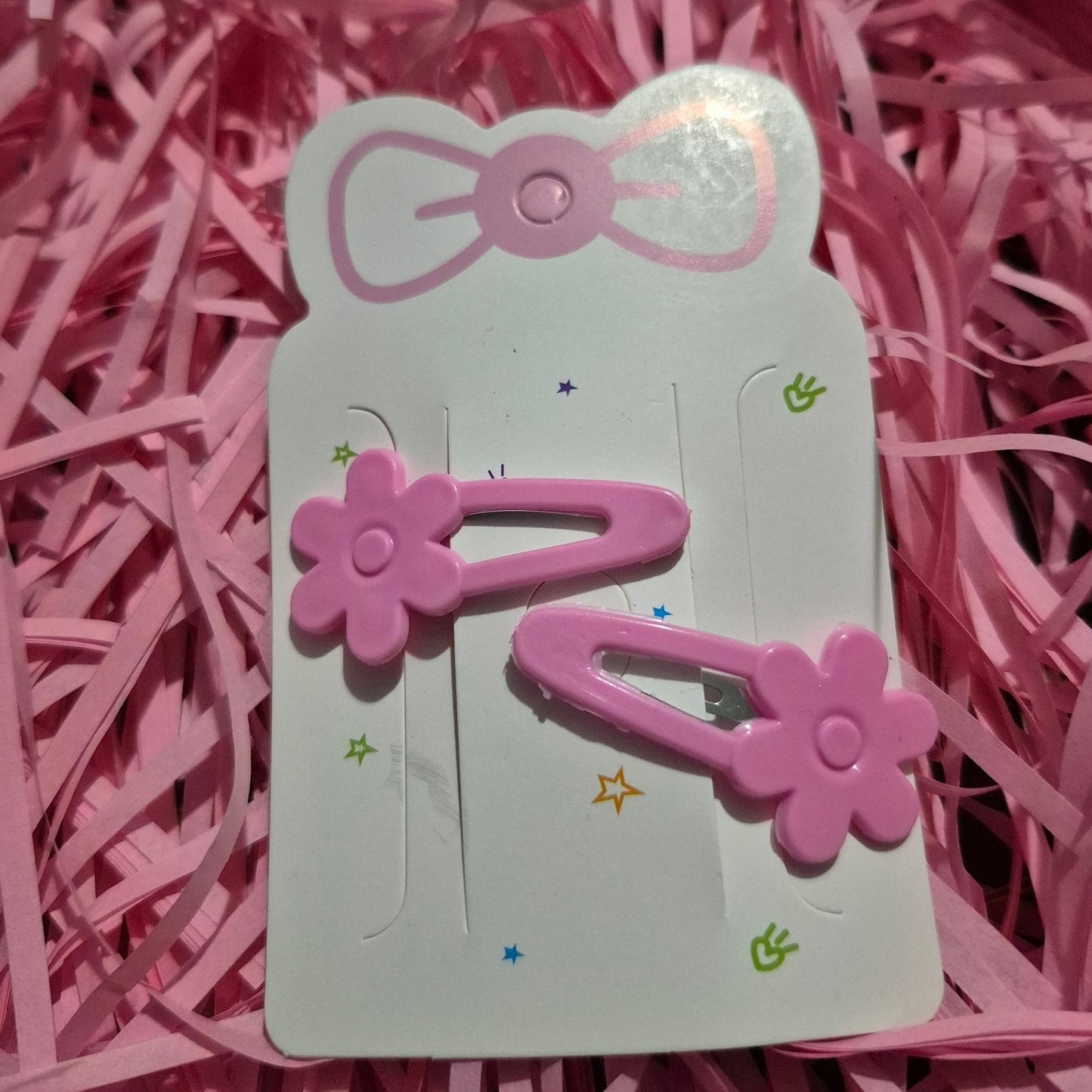 Decorative hair clip with a bow and flower design on a pink background