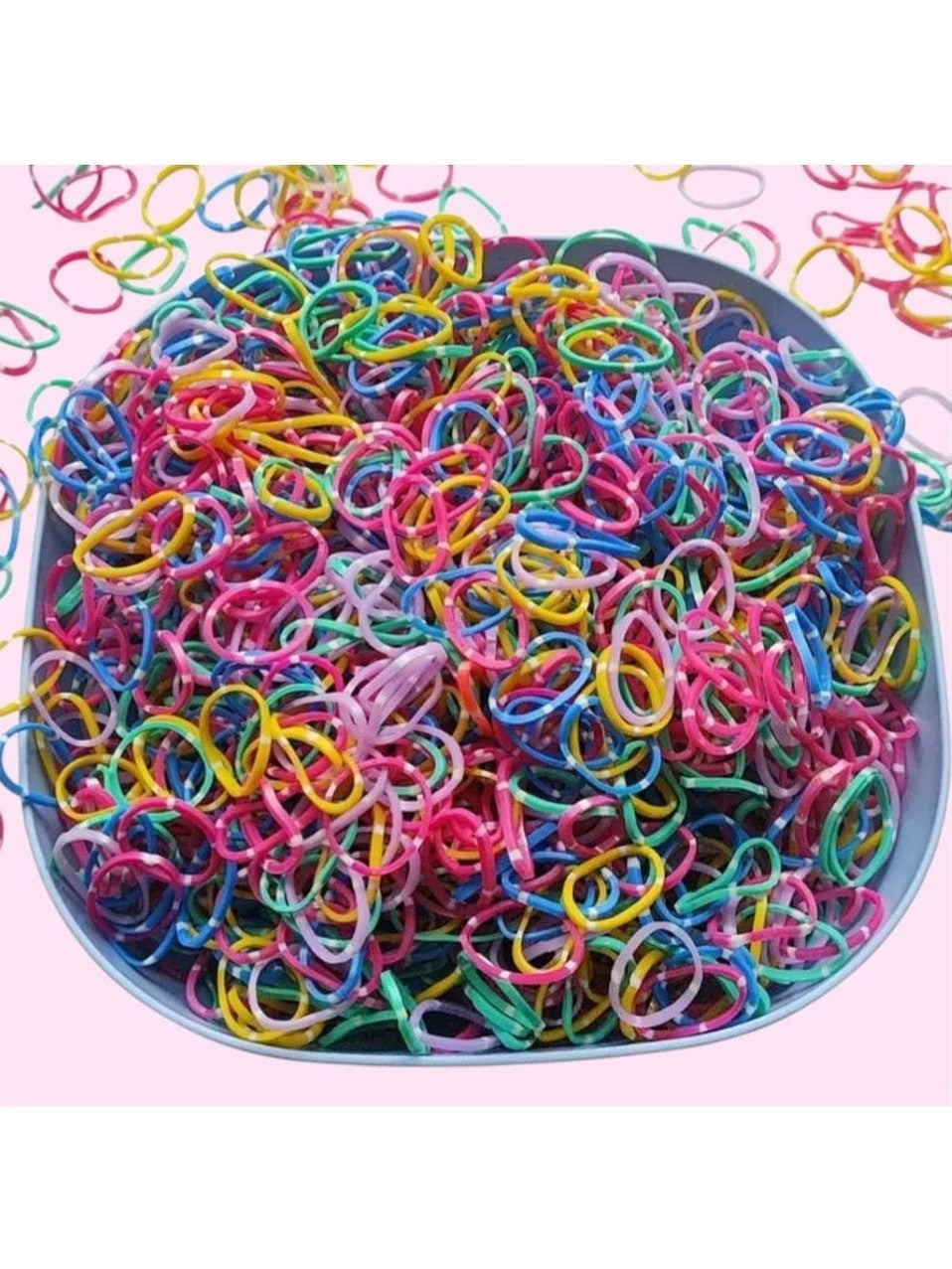 Assorted colorful rubber bands in a bowl on a pink background