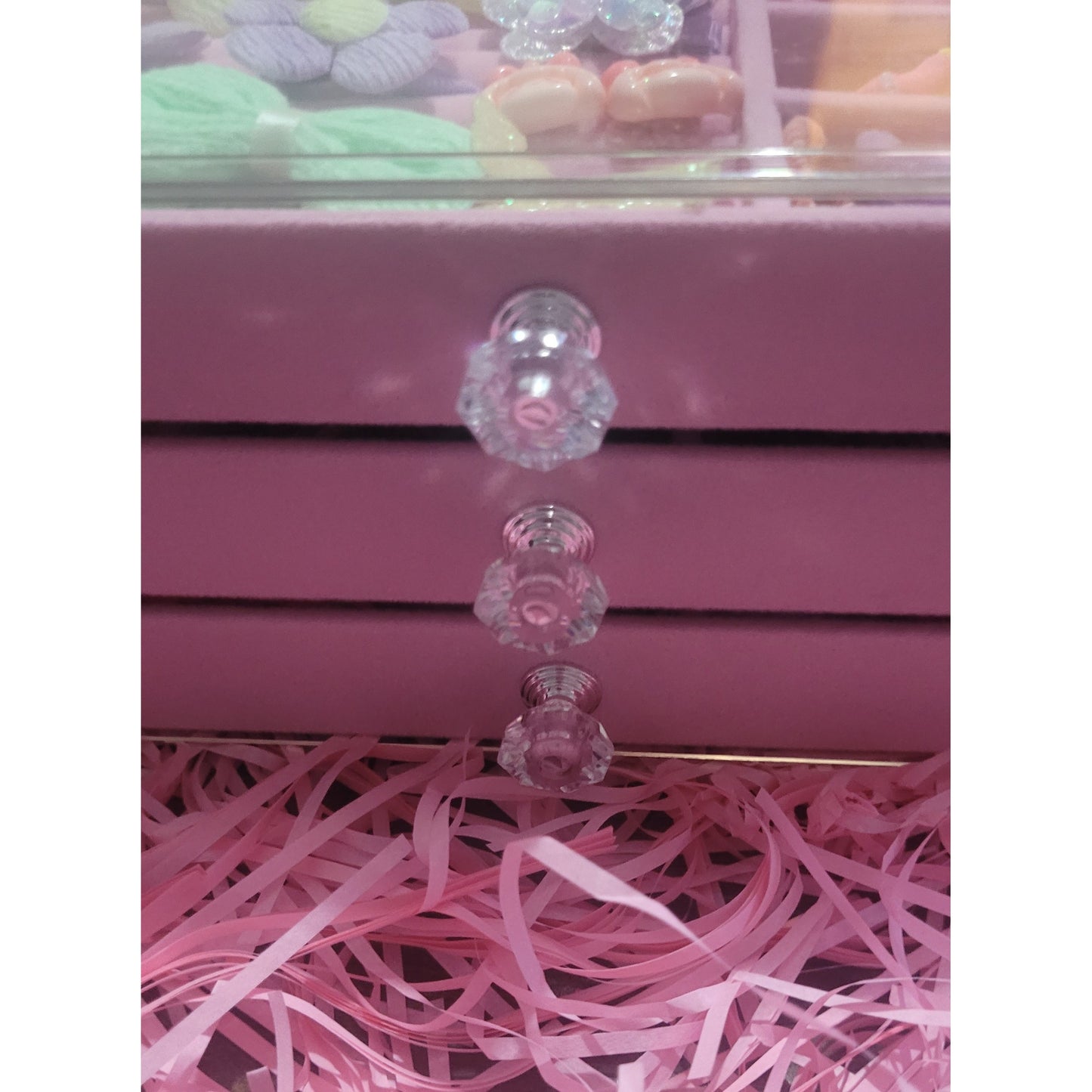 Close-up of a pink drawer with decorative glass knobs and pink ribbons.