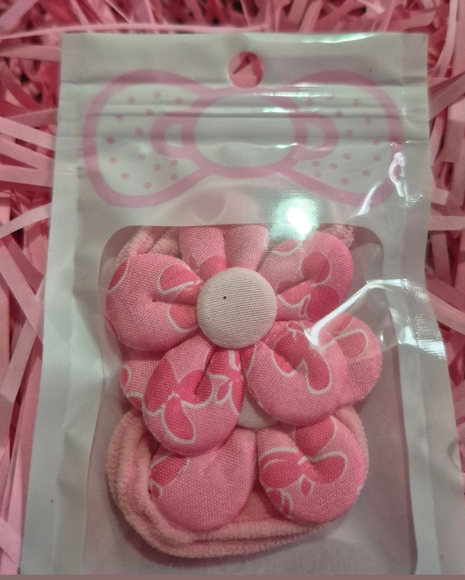 Pink hair ties in a clear package on a pink shredded paper background