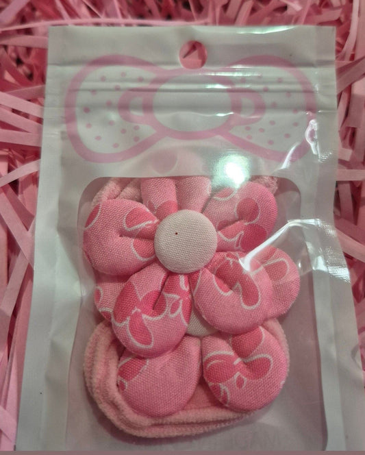 Pink hair ties in a clear package on a pink shredded paper background