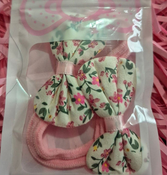 Set of floral hair accessories in a clear package on pink shredded paper