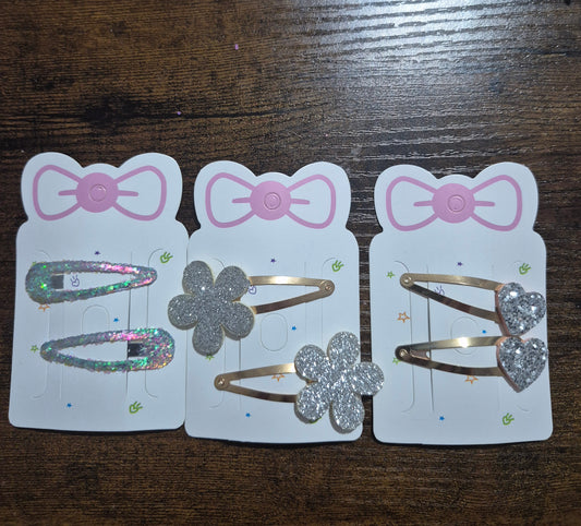 Three hair clip packages with decorative clips on a wooden surface