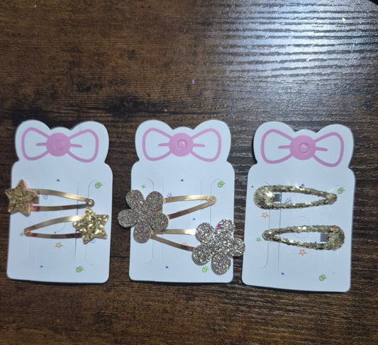 Three hair clip packages with decorative clips on a wooden surface