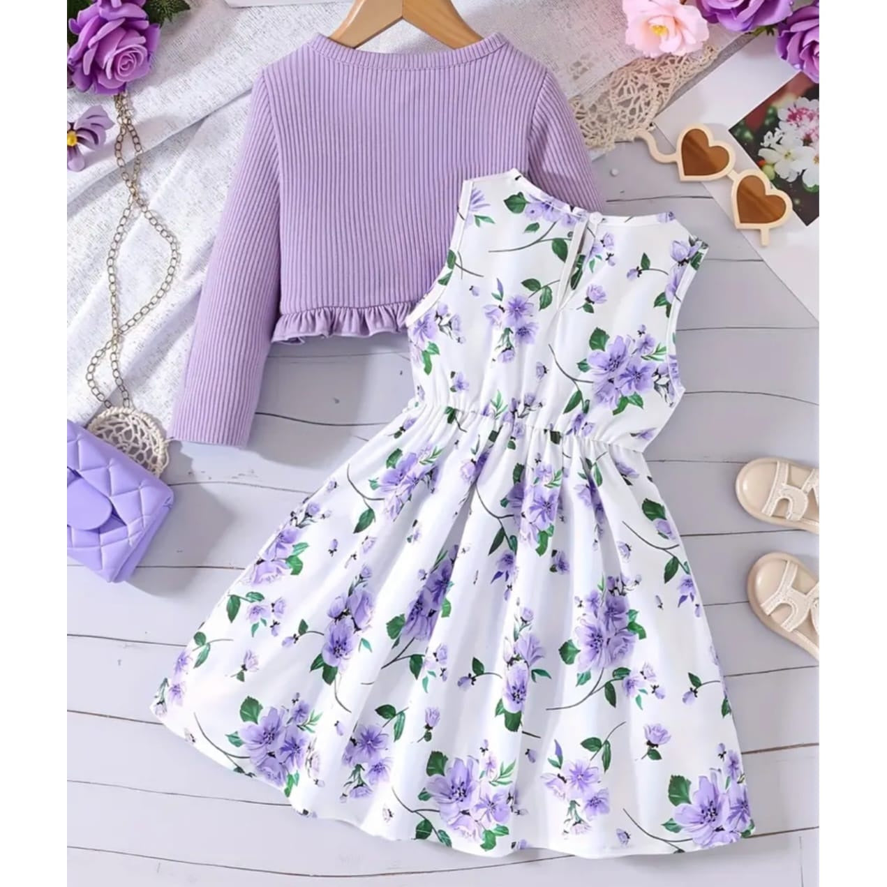 Purple top and floral skirt set on a light wooden floor with accessories.