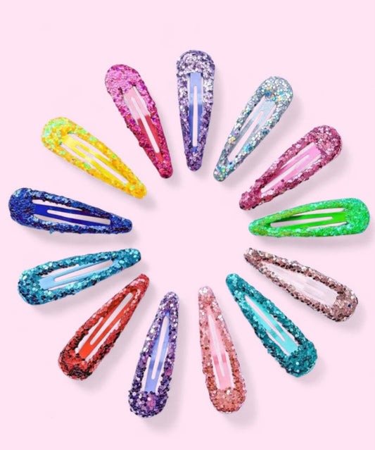Colorful glittery hair clips arranged in a circular pattern on a light pink background