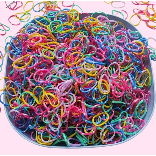 Assorted colorful rubber bands in a bowl on a pink background
