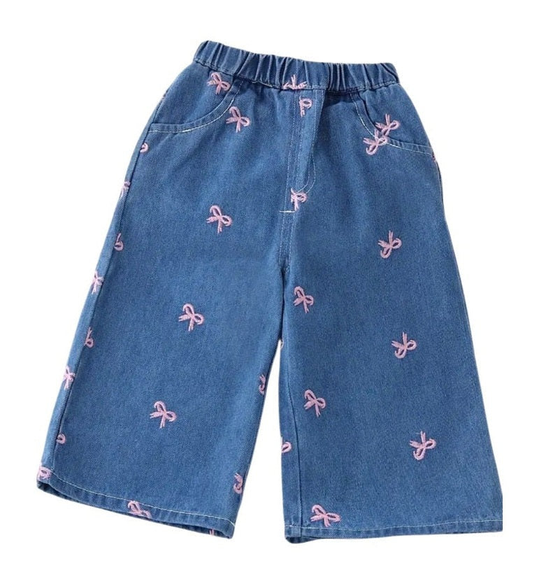 Blue denim pants with pink bow patterns on a white background