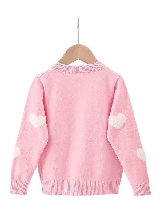 Pink sweater with white heart patterns on a hanger against a white background